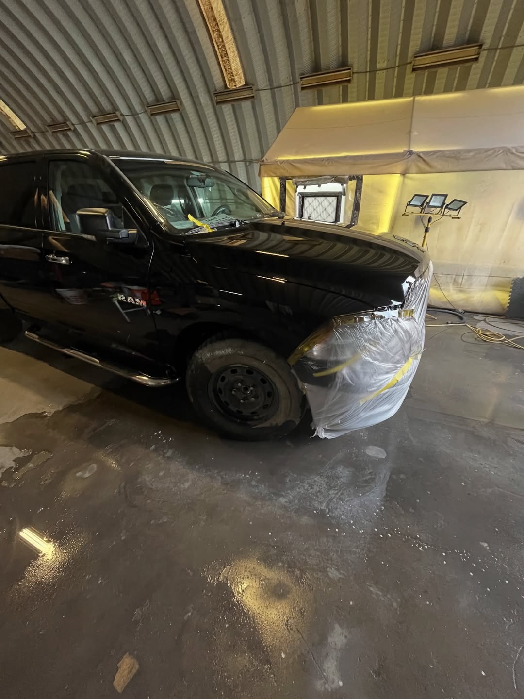 Dodge Ram 1500 in paint booth — front panel masked for color matching